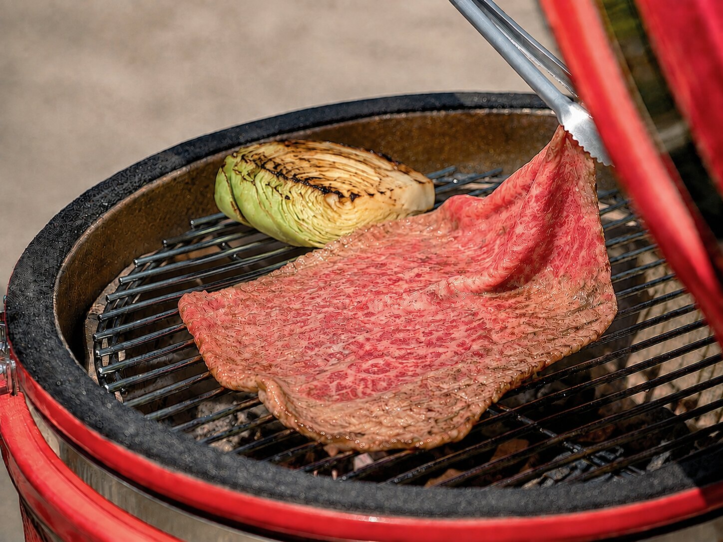炭火のグリルで焼かれる近江牛の大判一枚肉と焼き野菜